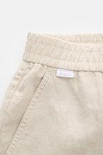 Nahaufnahme der beige 04651/ A trip in a bag Leinenshorts mit elastischem Bund, französischer Tasche und kleinem Weblabel, aus luftigem Leinenstoff.