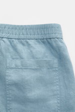 Rückansicht der rauchblauen 04651/ A trip in a bag Leinenshorts aus weichem, luftigen Leinen mit elastischem Bund, Gesäßtasche und kleinem Weblabel.