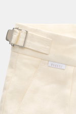 Detailaufnahme der 04651/ A trip in a bag Leinen-Shorts creme von schräg oben, zeigt Side-Adjuster, typisches Leinenmaterial, Bund mit Weblabel.
