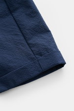 Nahaufnahme der fixierten Saumaufschläge der 04651/ A trip in a bag Seersucker-Shorts navy aus strukturtypischem Microfaser-Seersucker, fotografiert von schräg oben.