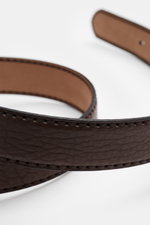 Close-up angled view of the Fausto Colato Gürtel Bisonleder dunkelbraun showing its textured dark brown grained bison leather, brass prong buckle, single loop, and Made in Italy craftsmanship, highlighting its practical and luxurious design.