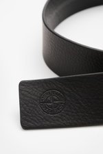 Stone Island Belt black photographed from a close-up side angle, showing elegant cowhide with characteristic grain, STONE ISLAND embossed logo, matt black pin buckle, one loop, small woven label, made in Italy, width 4 cm.