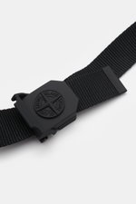 Close-up, angled top view of Stone Island Gürtel schwarz with woven black microfiber strap and matte black rubberized metal buckle featuring iconic compass logo.

<p>Dieser gewebte Gürtel von STONE ISLAND ist mit seiner gummierten mattschwarzen Koppelschl