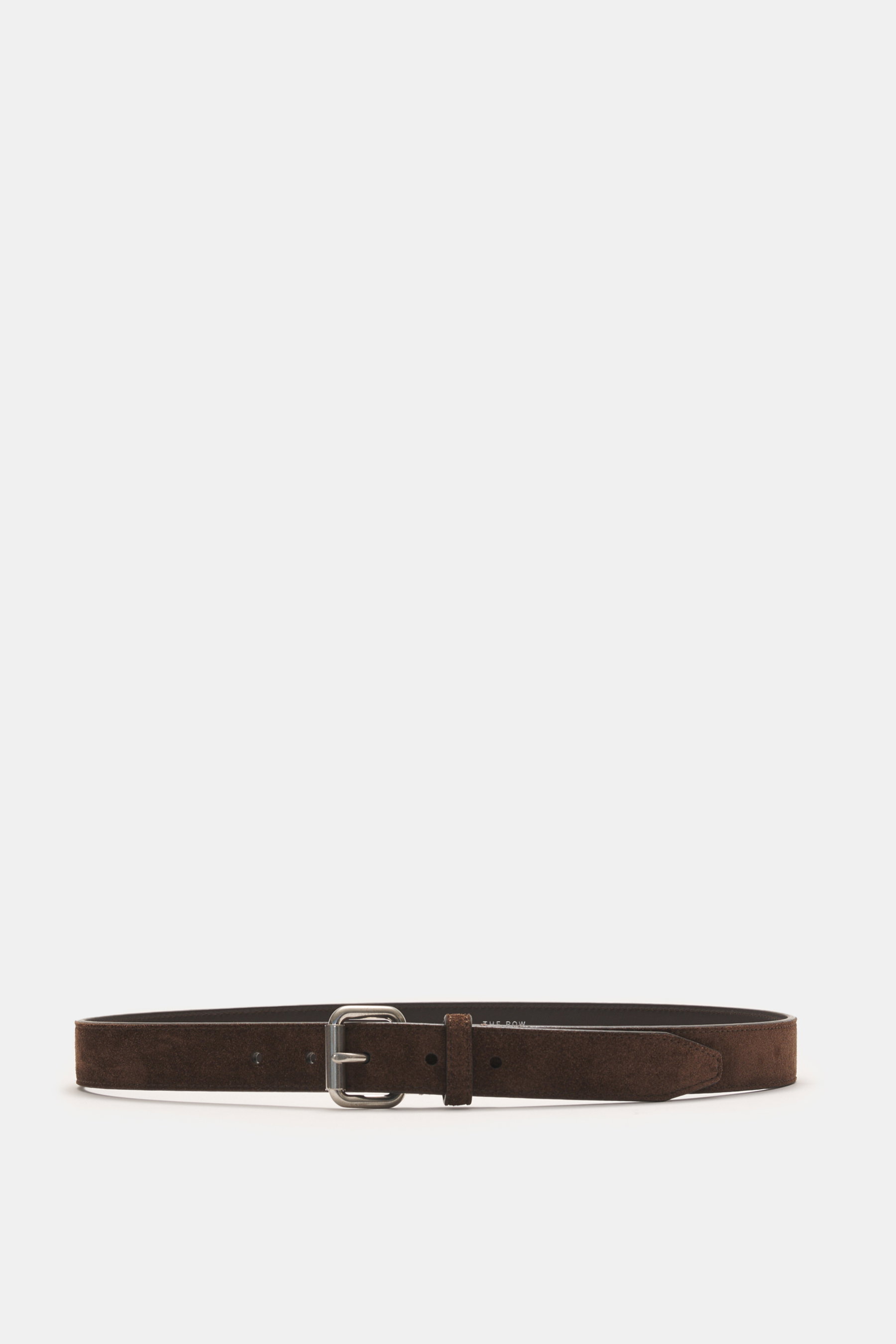 Front view of The Row Dark brown suede belt laid flat, featuring noble suede leather, brass prong buckle, one loop, approx. 2.5 cm wide, made in Italy. Finest quality from THE ROW: This top-class belt, made in Italy from noble suede leather, stands for th