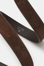 The Row Veloursledergürtel dunkelbraun, aus edlem Veloursleder mit Dornschließe aus Messing, schräg von oben fotografiert.