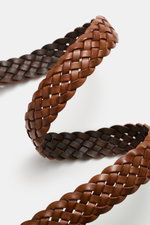 Ami Paris Braided belt brown photographed close-up from a side angle showing braided smooth leather construction, silver-colored prong buckle, and pull-through loop with logo; width approx. 3 cm. Timeless accessory: The braided belt from AMI PARIS proves 