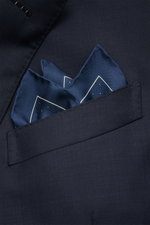 Tom Ford Silk pocket square grey-blue/white, with polka dots, pure silk, smooth feel, rolled edges, small TOM FORD print, made in Italy, approx. 39x39 cm, shown folded in a navy suit pocket from a close-up front angle.