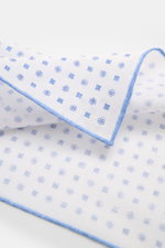 Rosi Collection Linen pocket square 'Fox' white/blue patterned shown from a close-up side angle, featuring pure linen, soft feel, floral print, rolled edges, made in Italy, dimensions 31.5 cm x 31.5 cm.