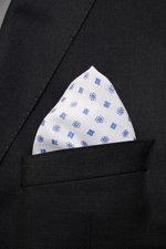 Front close-up view of the Rosi Collection Linen pocket square 'Fox' white/blue patterned in a black suit pocket, pure linen, soft feel, floral print, rolled edges, made in Italy, dimensions 31.5 cm x 31.5 cm.