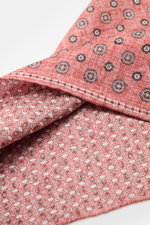 Rosi Collection Pocket square 'Joy' light red/white/black patterned shown close-up from an angled top view, with floral retro design, silk-linen blend, different front and back patterns, rolled edges, made in Italy, approx. 31x31 cm.