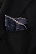 Close-up side view of a Brunello Cucinelli Silk pocket square navy/grey striped, tucked into a black blazer pocket, showcasing its smooth silk fabric and rolled edges.

Description: 
<p>Timeless refinement for sophisticated looks: The silk pocket square b