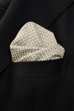 Brunello Cucinelli Silk pocket square sage/cream pattern with graphic micro print, pure silk, smooth feel, rolled edges, Made in Italy, approx. 35x35 cm, photographed close-up from front angle in black jacket pocket.