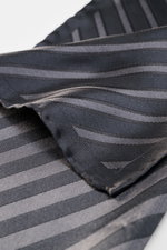 Close-up from a top angle of the Brunello Cucinelli Silk Pocket Square grey brown/brown striped, showing diagonal stripes and rolled edges.

<p>Subtle elegance for stylish appearances: With this noble pocket square in a subdued striped pattern, BRUNELLO C