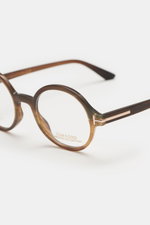 Close-up front-side view of Tom Ford Horn glasses 'Private Collection' brown patterned with round design, buffalo horn frame, T-shaped details.