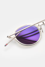 Runde Thom Browne Sonnenbrille silbergrau mit tiefem Metallrahmen und Tricolore-Detail am Bügel, Nahaufnahme von oben mit leicht getönten Gläsern.