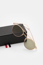 Runde Thom Browne Sonnenbrille gold mit filigranem Metallrahmen, getönten Gläsern, Tricolore-Detail am Bügel, seitliche Perspektive.