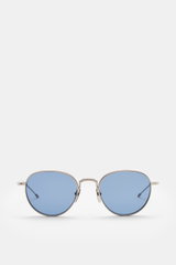 Frontale Nahaufnahme der Thom Browne Sonnenbrille hellgrau mit abgerundeter Form, transparentem Acetat-Rahmen, blauen Kunststoffgläsern und Tricolore-Detail am Bügel.