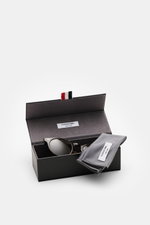 Thom Browne Sonnenbrille braun gemustert in klassischer Notched-Bridge-Form mit getönten Gläsern, Acetat-Rahmen, Hartschalenetui, von oben fotografiert.