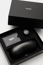 Schwarze Lederbox mit Tom Ford Horn-Sonnenbrille 'Private Collection' graubraun, Leder-Etui, Horn-Politurset und Putztuch von oben fotografiert.