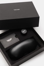 Geöffnete schwarze Geschenkbox mit Tom Ford Horn-Sonnenbrille 'Private Collection' anthrazit gemustert/gelb im Leder-Hartschalenetui, Politurset und Servicekarte von oben fotografiert.