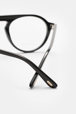 Close-up rear view of Tom Ford Horn Brille 'Private Collection' schwarz/grau/weiß gemustert with round genuine buffalo horn frame, blue light filter lenses, T-shaped details, photographed from the back crossing the black temples. Stilvoller Eyecatcher: Di