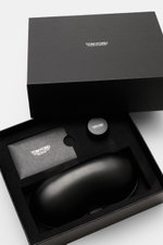 Geöffnete schwarze Box mit Tom Ford Horn Brille 'Private Collection' schwarz/grau gemustert inklusive Lederetui, Horn-Politurset und Putztuch, seitliche Perspektive.