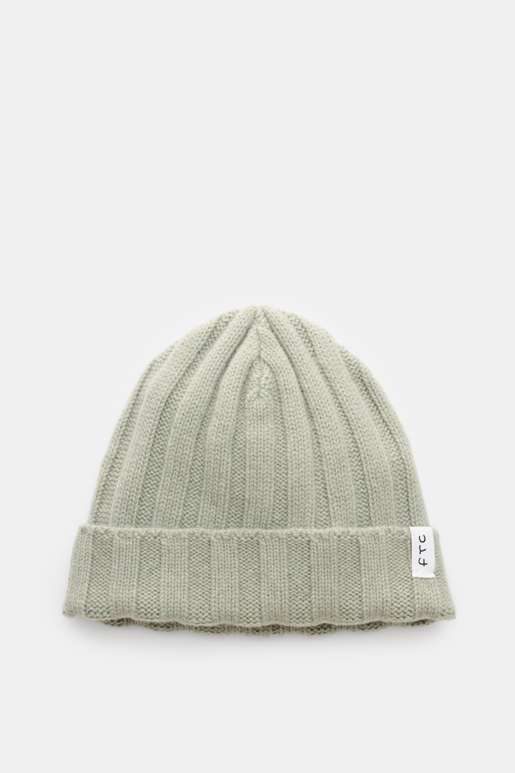 FTC Cashmere Mütze graugrün aus feinstem Fair-Trade-Cashmere, mittelfeiner Rippstrick, weicher Griff, schmaler Umschlag mit FTC-Weblabel, von oben fotografiert.