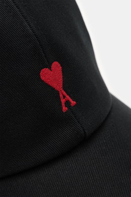 Nahaufnahme der Ami Paris Baseball-Cap schwarz aus reiner Baumwolle mit rotem Herz-Logo, weichem Griff und gebogenem Schirm, von schräg vorne fotografiert.