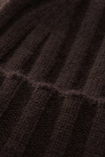 Nahaufnahme der von Braun Cashmere Mütze dunkelbraun aus reinem mongolischem Cashmere, feines Strickbild mit klassischem Rippstrick und schmalem Umschlag, sehr weicher Griff, fotografiert von oben.