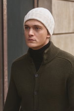Front view of a man wearing a von Braun Cashmere beanie off-white, soft pure cashmere, fine rib knit, small turn-up, styled with a dark green cardigan and black turtleneck. Whether worn with a classic winter coat or a functional down jacket, this knitted 