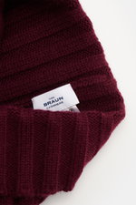 Close-up top-down view of von Braun Cashmere beanie burgundy showing fine rib knit pattern and label, made of pure soft Mongolian cashmere.