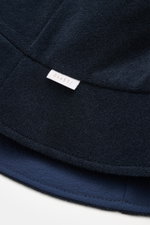 04651/ A trip in a bag Wende-Frottee Bucket Hat navy aus elastischem Baumwoll-Frottee mit schmaler Krempe, weichem Griff und kleinem Weblabel, Detailaufnahme von unten.