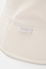 04651/ A trip in a bag Wende-Frottee Bucket Hat weiß, Detailaufnahme der schmalen Krempe mit kleinem Weblabel, elastischer Baumwoll-Frottee, innen Seersucker, wendbar, softer Griff.