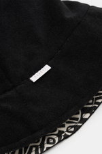 04651/ A trip in a bag Wende-Frottee Bucket Hat schwarz, Detailaufnahme von oben, elastischer Baumwollfrottee mit gemustertem Innenfutter, schmale Krempe, weiches Material, kleines Weblabel sichtbar.
