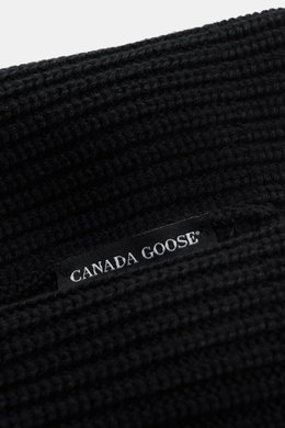 Close-up angled view of Canada Goose Wool beanie black showing chunky pure wool rib knit and woven label, robust fabric, turn-up style. 

<p>A must-have for the colder months: Don’t let bad hair days or cold winter days get to you with this beanie in pure