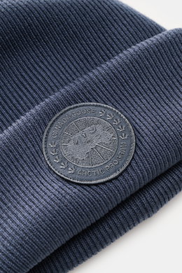 Canada Goose Wollmütze 'Arctic Toque' graublau aus reiner Wolle in feinem Rippstrick, doppellagig mit Umschlag und monochromem Weblabel, Nahaufnahme schräg von oben.