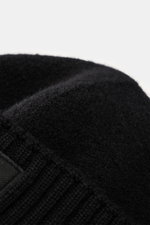 Close-up angled view of the Stone Island Wool beanie black showing pure virgin wool, soft touch, wide rib-knit cuff, and front with STONE ISLAND woven label.