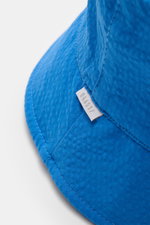 Nahaufnahme aus seitlicher Perspektive des 04651/ A trip in a bag Wende-Frottee Bucket Hat blau mit schmaler Krempe, Baumwoll-Frottee, Seersucker-Futter und kleinem Weblabel.