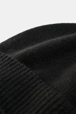Close-up view of Emporio Armani Cap black showing soft touch, fine knit pattern, narrow cuff, mix of cashmere and microfiber, and leather logo patch.