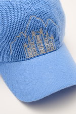 Close-up front-side view of the 04651/ A trip in a bag Cashmere Baseball-Cap blau in soft blue, featuring fine knit visor and stitched Milan Cathedral and Cortina mountain peaks.

<p class="p1">Luxuriöses Winter-Highlight: Die Baseball-Cap aus der 'Look