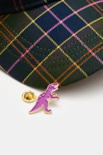 Nahaufnahme des Schirms der Barbour Baseball-Cap oliv/navy/orange kariert mit tartantypischem Muster und lila T-Rex-Pin, Perspektive von oben.