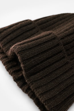 Nahaufnahme der Fedeli Cashmere Mütze dunkelbraun im Rippstrick mit weichem Griff und variablem Umschlag, fotografiert aus schräger Perspektive.