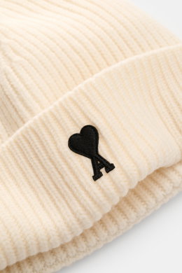 Ami Paris Wool beanie cream shown from a close-up angled top view, featuring pure virgin wool, slightly grippy texture, classic rib knit pattern, wide cuff, and typical logo patch.