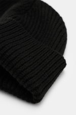 Ami Paris Wool beanie black shown from a top-down close-up perspective, featuring pure virgin wool, slightly grippy texture, classic rib knit pattern, wide cuff, and typical logo patch.
