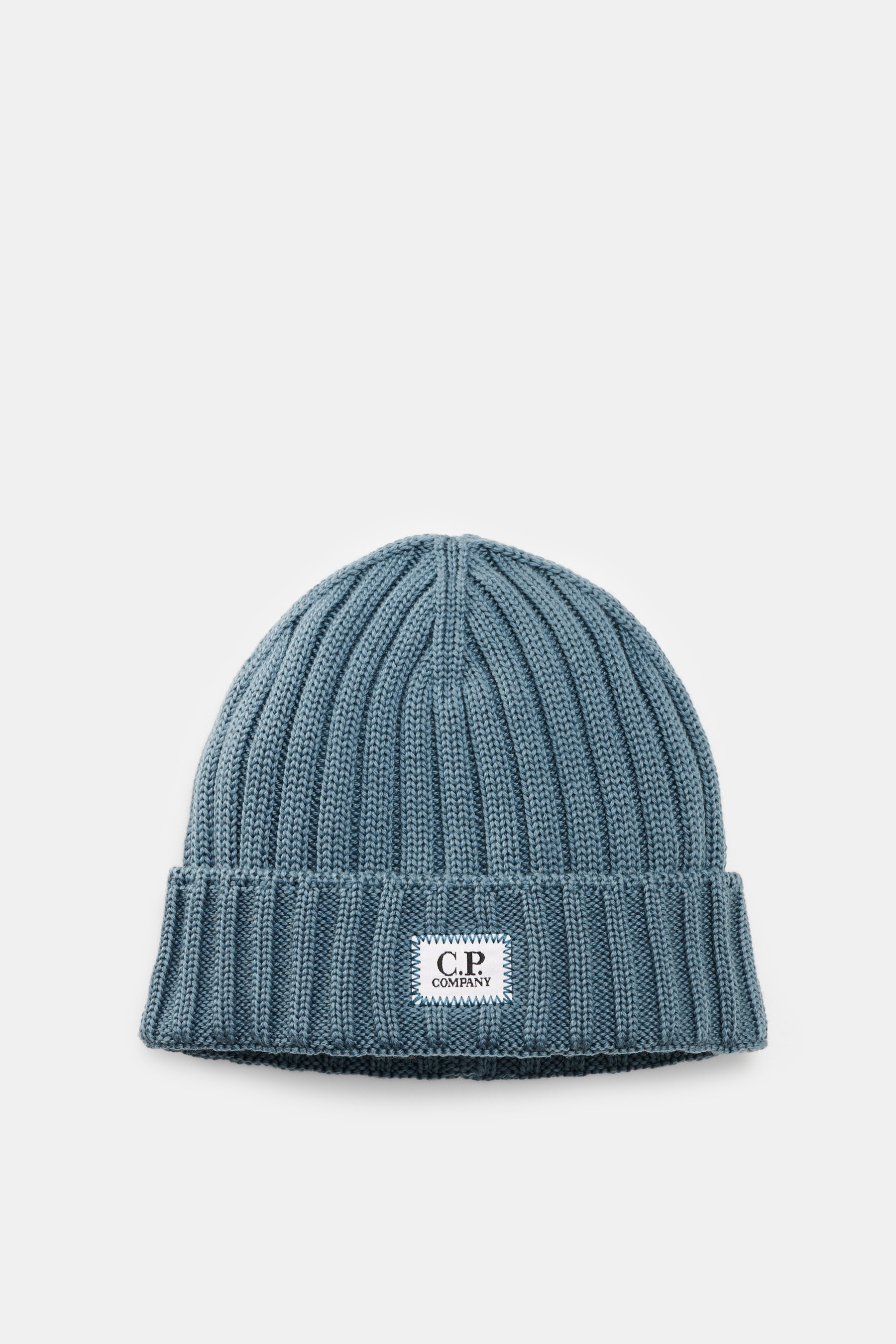 Top-down view of C.P. Company Wool beanie smoky blue, featuring pure virgin wool, soft touch, classic rib knit pattern, medium coarse knit texture, cuff with logo patch.