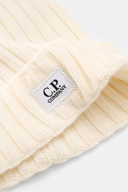 Close-up, angled view of the C.P. Company Merino beanie cream showing pure merino wool, soft feel, classic ribbed knit pattern, medium coarse knit texture, and cuff with logo patch.