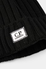 Close-up front view of C.P. Company Merino Mütze black showing pure Merino wool, soft touch, classic rib knit, medium knit texture, and folded cuff with logo patch.