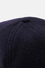 Close-up top view of Officine Générale Wool baseball cap 'Jason Cap Double Split' navy showing pure wool fabric with soft touch, classic six-panel design, and button detail.