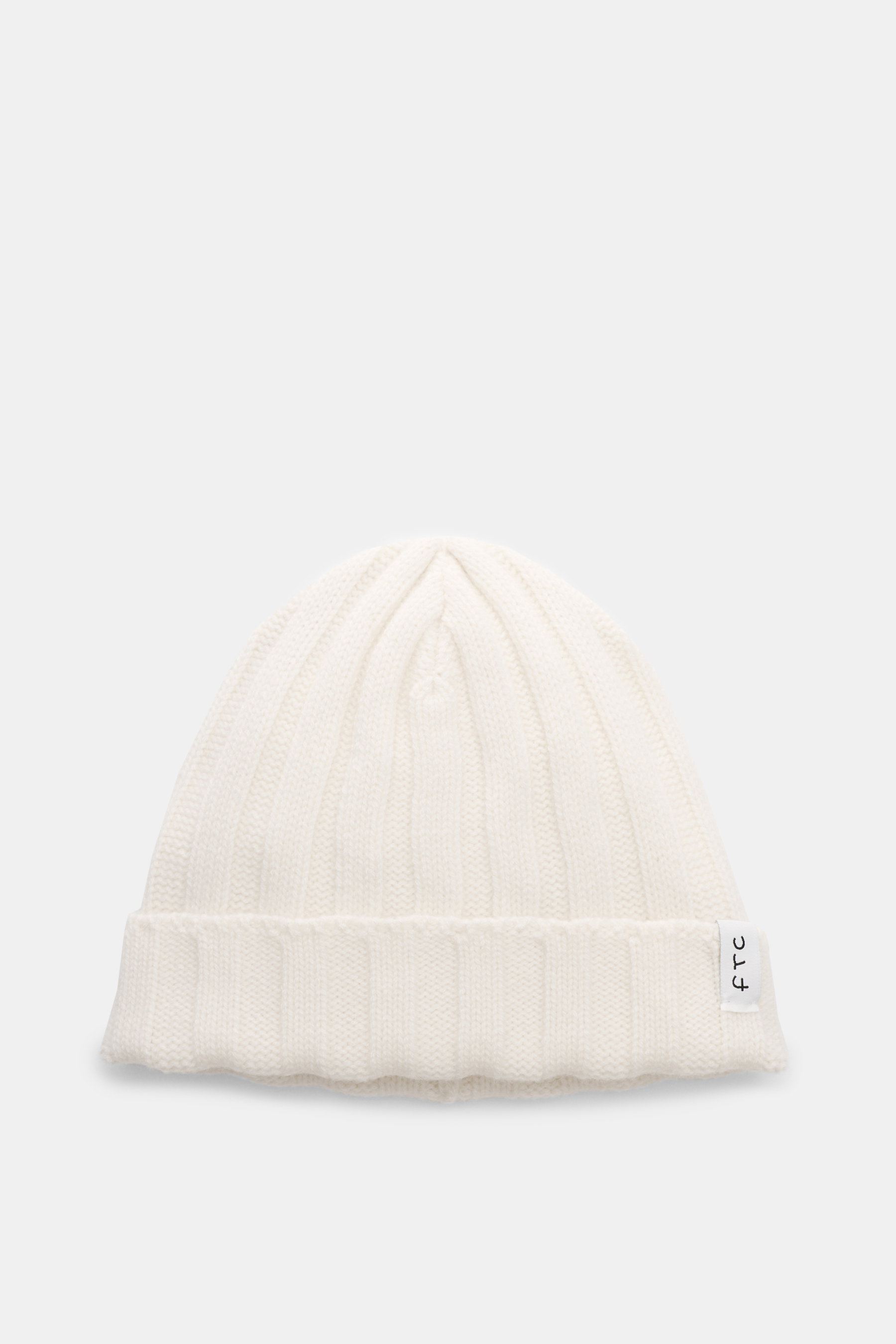 Front view of FTC Cashmere Beanie offwhite, a luxurious winter accessory with ribbed knit pattern, medium-fine texture, narrow cuff, and FTC label. Pure cashmere, very soft feel.