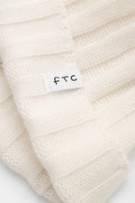 Close-up front view of the FTC Cashmere Beanie offwhite showing its ribbed knit pattern, narrow cuff, and FTC woven label. Luxurious winter accessory: This ribbed knit beanie is made from finest fair-trade cashmere and is a classic that should not be miss
